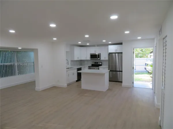 a large kitchen with stainless steel appliances a refrigerator and a stove top oven