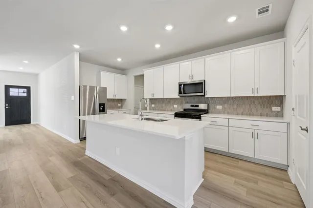 a kitchen with stainless steel appliances granite countertop a refrigerator stove top oven and sink