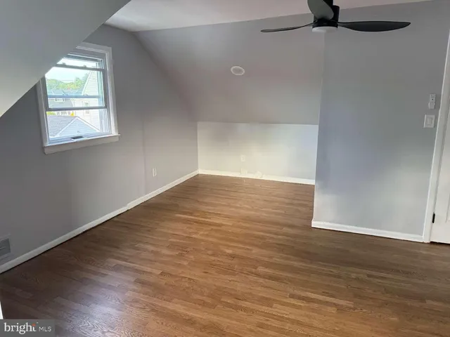 an empty room with wooden floor cabinet and windows