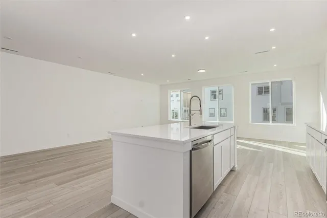 a kitchen with a sink and dishwasher with wooden floor