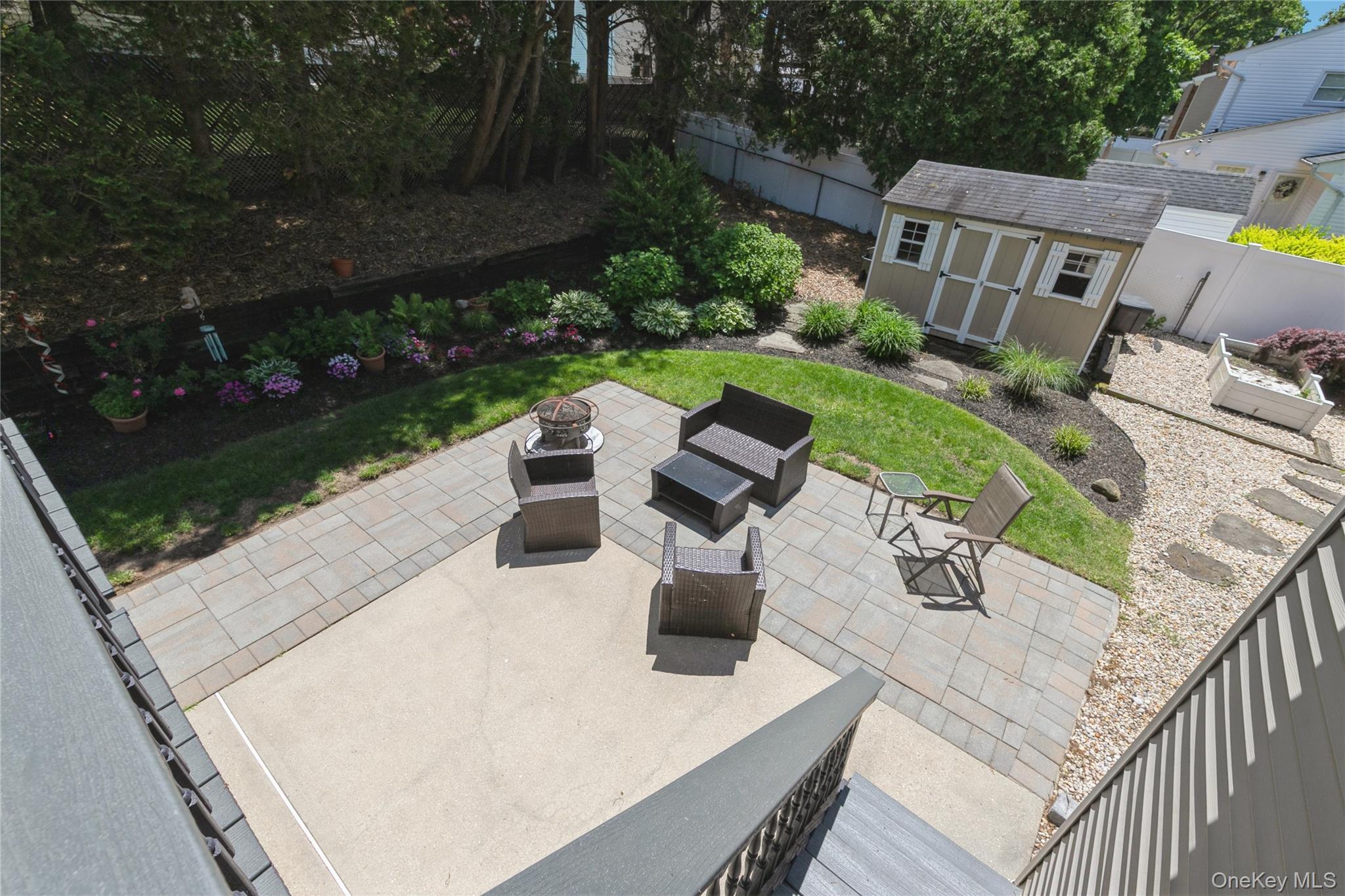 115 Clarendon Road Ronkonkoma, NY 11779 - Photo 33 of 45 Expansive backyard featuring a paver patio with a concrete section, manicured lawn, and a storage shed with white window shutters