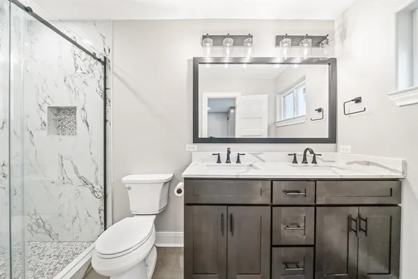 a bathroom with a granite countertop sink a toilet and a mirror