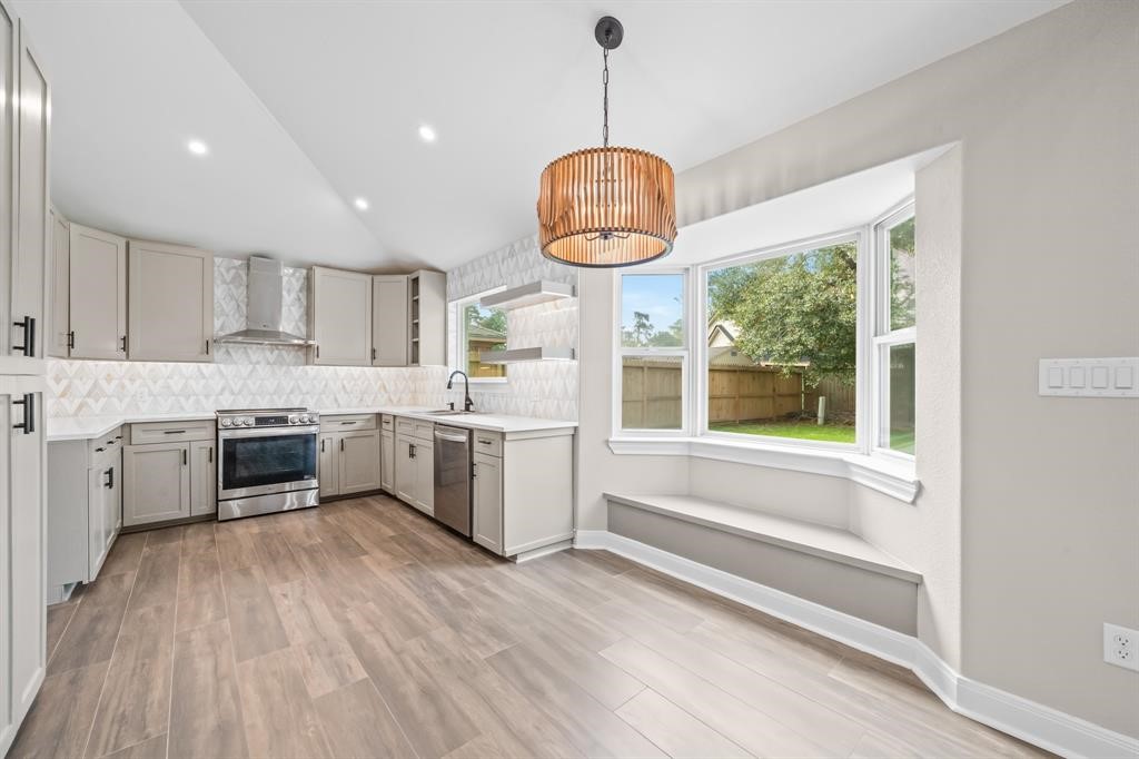 23307 Apple Arbor Drive Spring, TX 77373 - Photo 26 of 32 a kitchen with stainless steel appliances a stove a sink a kitchen island a stove and a wooden floors
