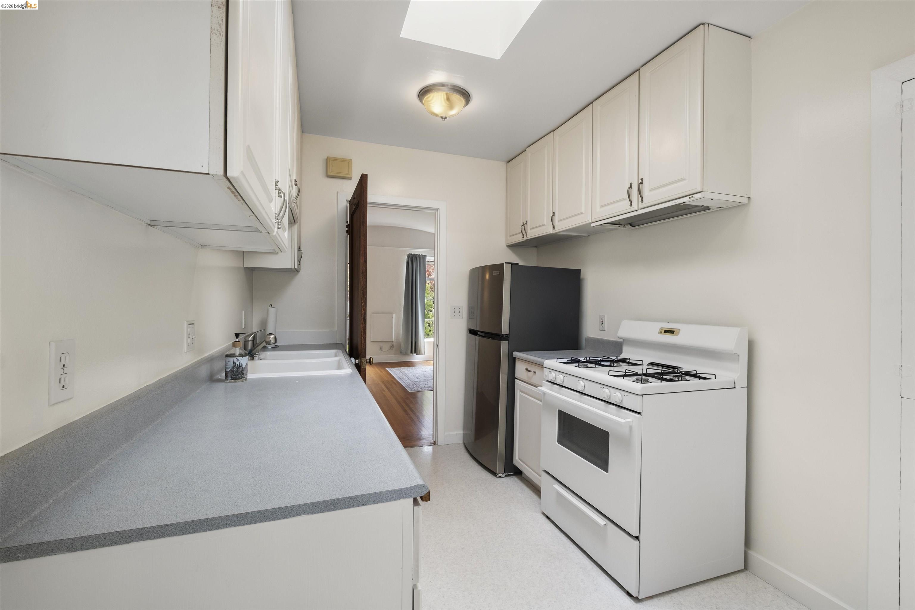 2444 Virginia Street, Unit B Berkeley, CA 94709 - Photo 26 of 39 Galley kitchen featuring white cabinetry, grey countertops, a double basin sink, and a gas range