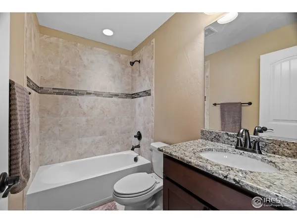 a bathroom with a granite countertop sink toilet mirror and bathtub