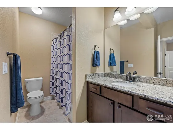 a bathroom with a granite countertop sink a toilet and a large mirror