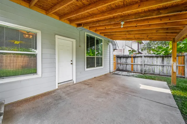 a view of backyard with large tree and wooden fence