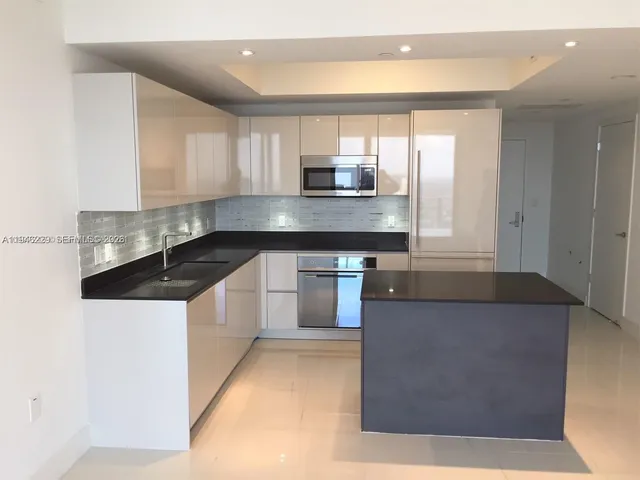 a kitchen with granite countertop a stove a sink and a microwave