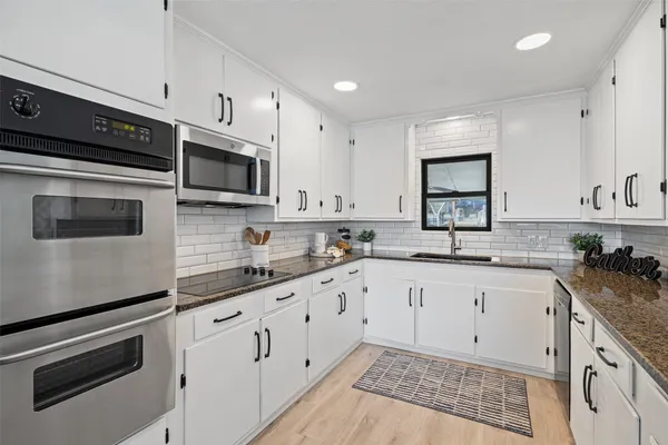 a kitchen with granite countertop white cabinets white stainless steel appliances and a sink
