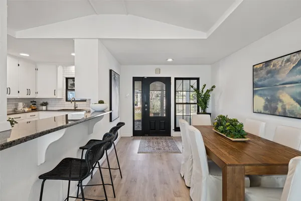 a large white kitchen with sink and dining table