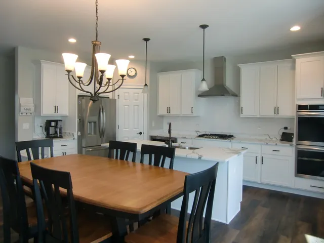 a kitchen with stainless steel appliances granite countertop a kitchen island a stove a table and chairs