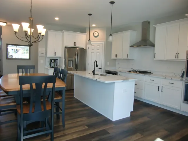 a kitchen with cabinets a stove a sink a dining table and chairs