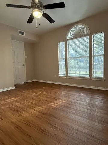 a view of an empty room with wooden floor and a window