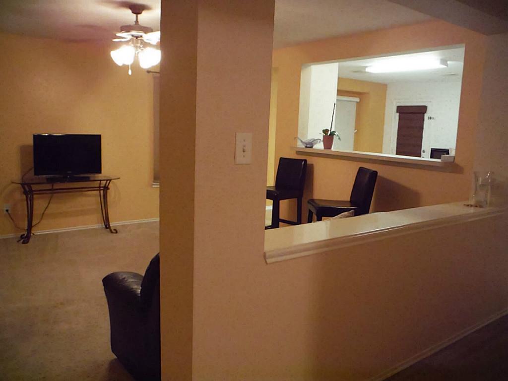 3142 Aspen Fair Trail Spring, TX 77389 - Photo 9 of 22 This photo shows a cozy living area with a warm color scheme, featuring a ceiling fan. The adjoining space includes a breakfast bar, and a hallway view into the living room, and a partial view of the kitchen.