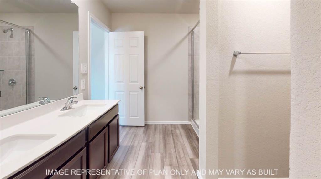10409 Altair Drive Waco, TX 76708 - Photo 6 of 11 Spa-inspired primary bathroom featuring a double-sink vanity with dark cabinetry, quartz countertop, and chrome fixtures