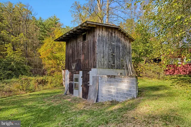 a view of a wooden house with a small yard and large trees