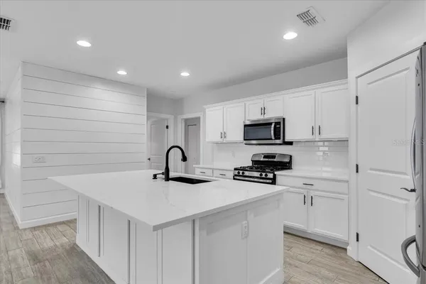 a close view of a sink a faucet and a refrigerator in a kitchen