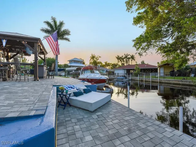 a patio area with table and chairs potted plants and a large tree