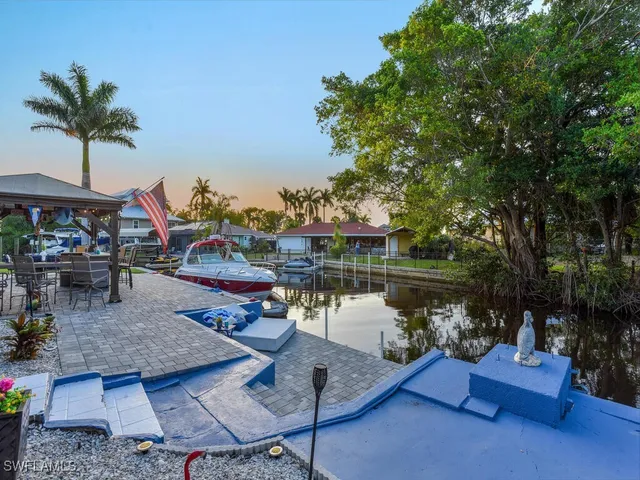 a view of a lake with couches table and chairs under an umbrella
