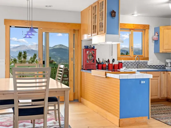 a dining room with wooden floor a chandelier a wooden table and chairs