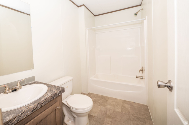 2491 Highway 89, Unit 403 Pleasant View, UT 84404 - Photo 24 of 32 Bathroom featuring a vanity with an integrated sink, a dark patterned countertop, wood-finish cabinetry, a white toilet, and a white shower/tub combination with a chrome shower head and faucet
