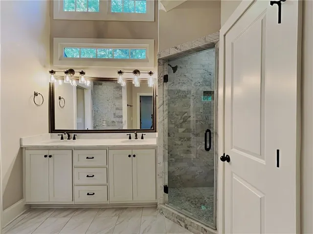a bathroom with a granite countertop sink a mirror and shower