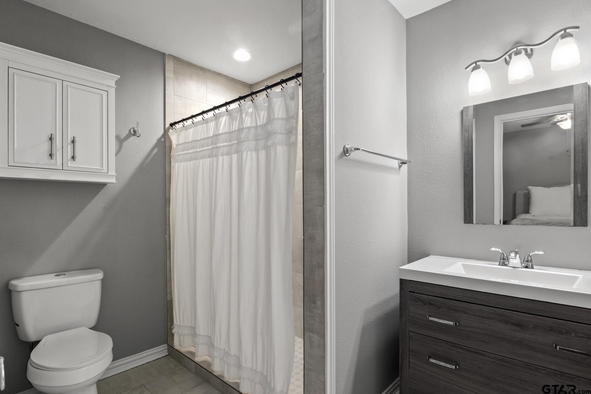 655 Daingerfield Street Pittsburg, TX 75686 - Photo 16 of 27 a bathroom with a toilet a sink a vanity and mirror