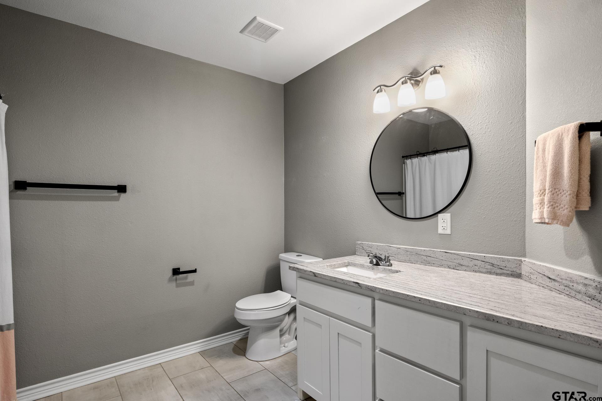 655 Daingerfield Street Pittsburg, TX 75686 - Photo 26 of 27 a bathroom with a granite countertop toilet a sink and a mirror
