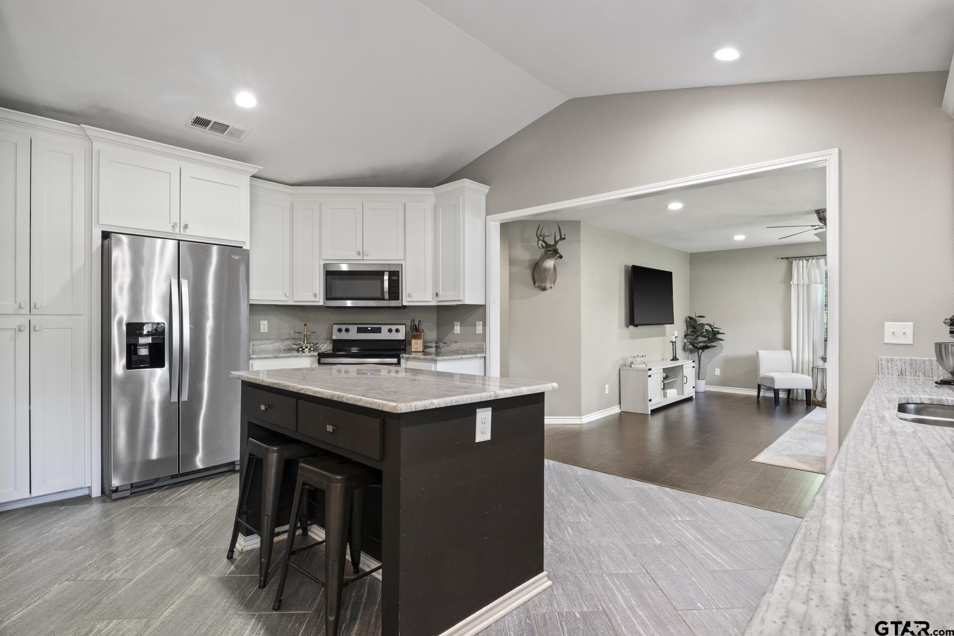 655 Daingerfield Street Pittsburg, TX 75686 - Photo 9 of 27 a kitchen with stainless steel appliances granite countertop a refrigerator a stove a sink a dining table and chairs with wooden floor