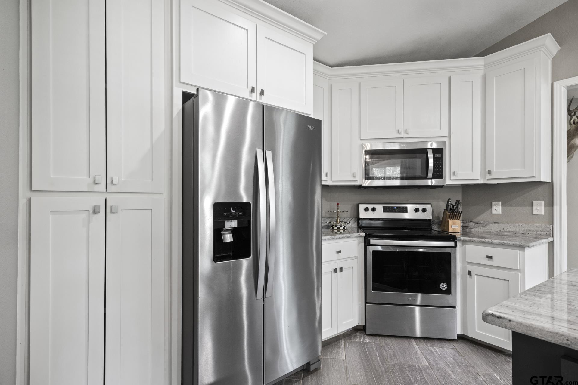655 Daingerfield Street Pittsburg, TX 75686 - Photo 10 of 27 a kitchen with stainless steel appliances a refrigerator stove and white cabinets