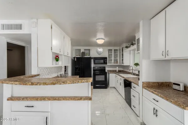 a kitchen with granite countertop a sink stainless steel appliances and white cabinets