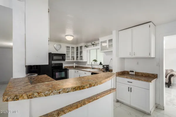 a kitchen with granite countertop a sink stove and cabinets