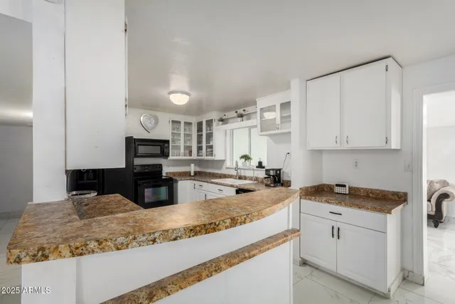 a kitchen with granite countertop a sink stove and cabinets