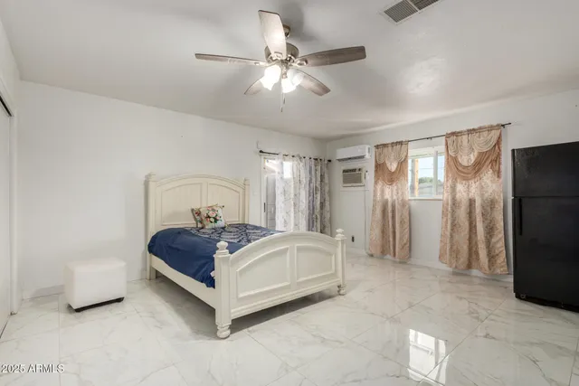 a white bed sitting in a room next to a window and a chandelier