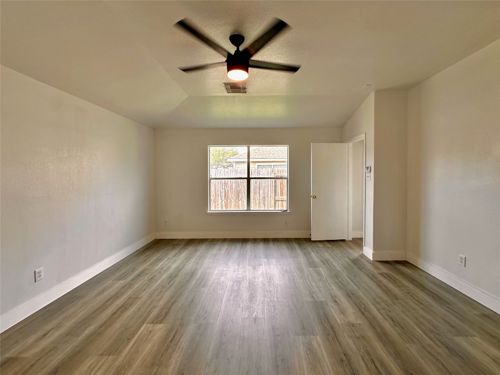 8202 Radial Court Rosharon, TX 77583 - Photo 16 of 27 an empty room with wooden floor chandelier fan and windows