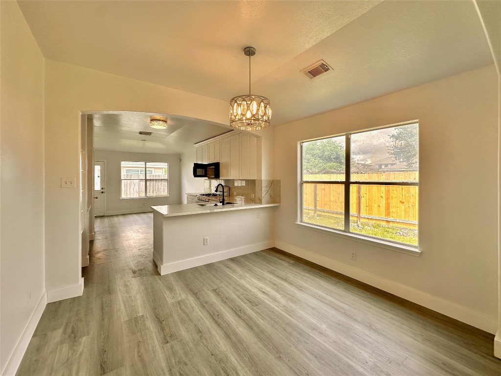 8202 Radial Court Rosharon, TX 77583 - Photo 5 of 27 a large kitchen with cabinets a sink dishwasher a dining table and chairs with wooden floor