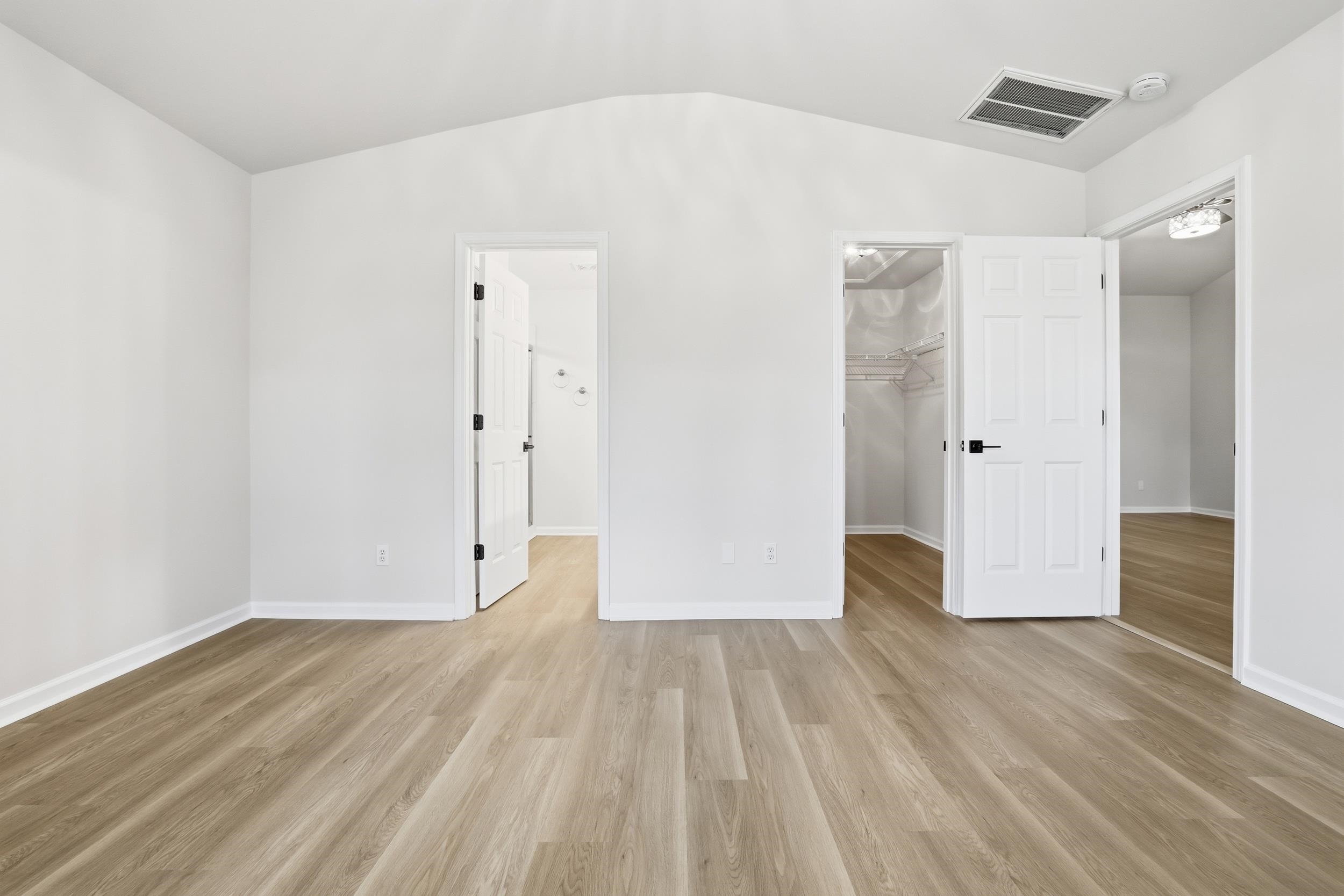 4566 Fringetree Drive Murrells Inlet, SC 29576 - Photo 12 of 36 Unfurnished bedroom with vaulted ceiling, a walk in closet, and light wood-type flooring