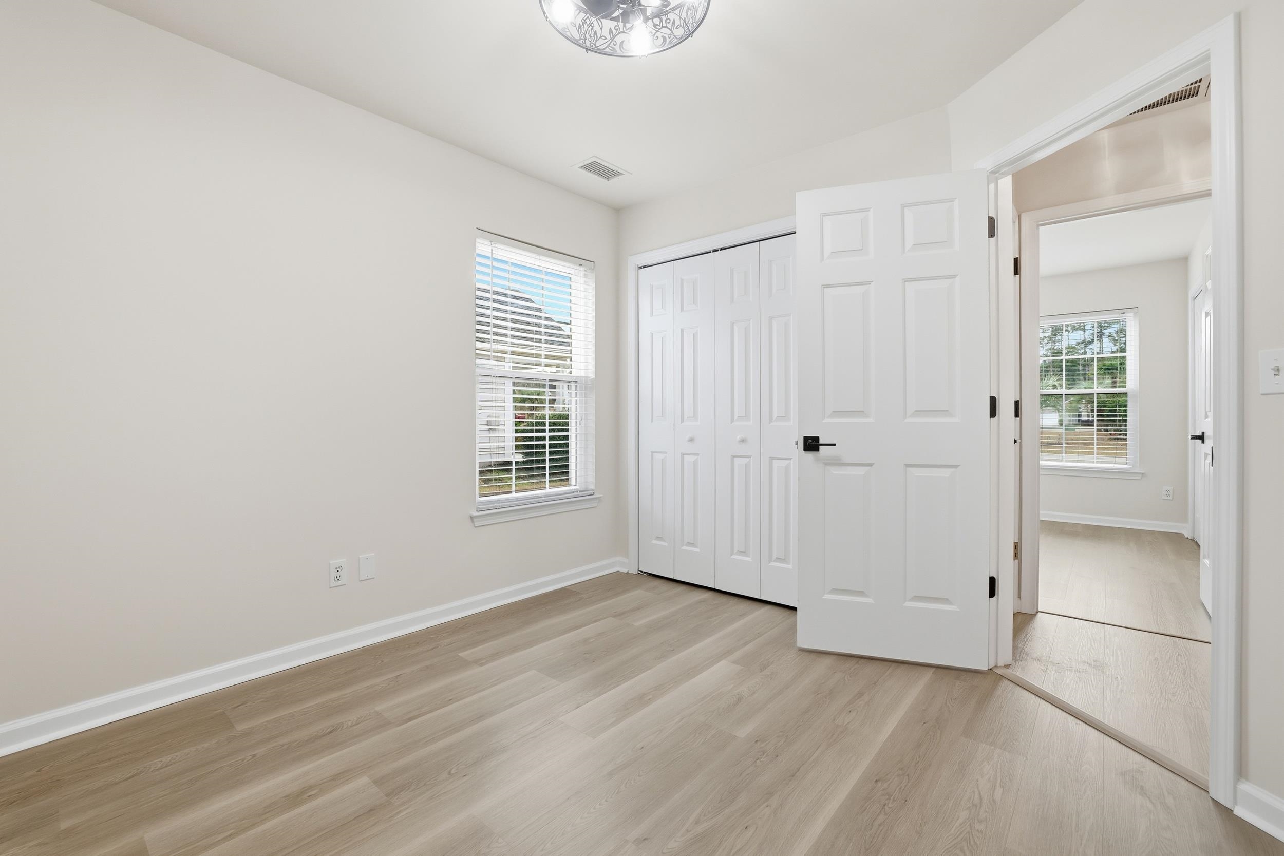 4566 Fringetree Drive Murrells Inlet, SC 29576 - Photo 19 of 36 Unfurnished bedroom with light wood-style flooring, multiple windows, and a closet