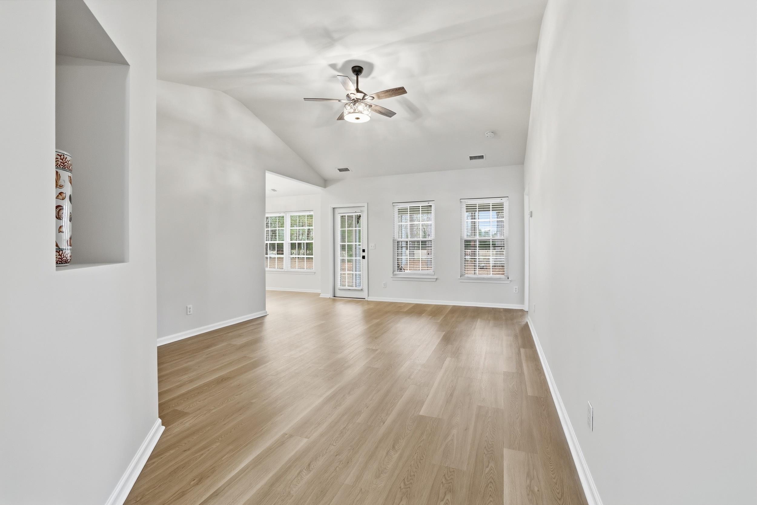 4566 Fringetree Drive Murrells Inlet, SC 29576 - Photo 5 of 36 Unfurnished living room with light wood-type flooring, lofted ceiling, plenty of natural light, and a ceiling fan