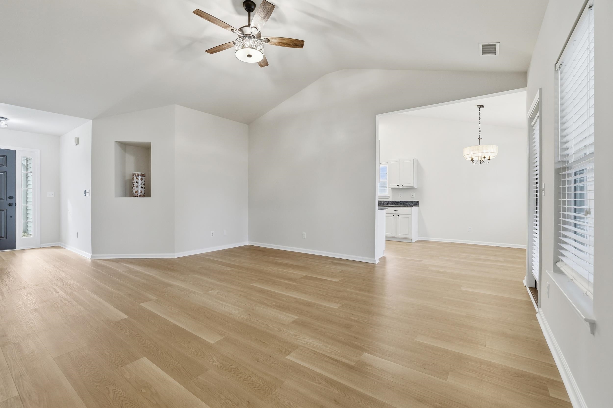 4566 Fringetree Drive Murrells Inlet, SC 29576 - Photo 6 of 36 Unfurnished living room featuring light wood finished floors, ceiling fan, lofted ceiling, and a chandelier