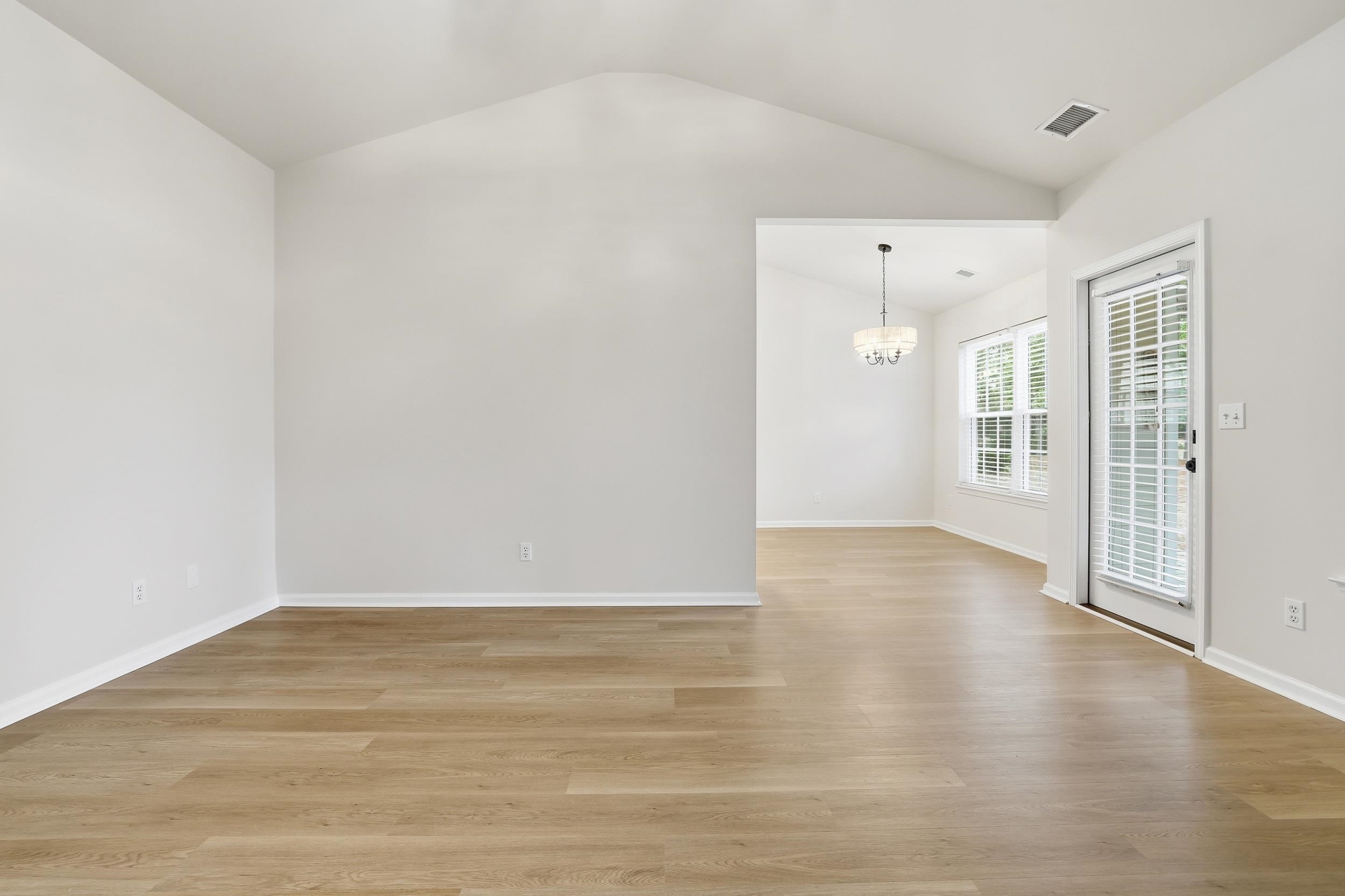4566 Fringetree Drive Murrells Inlet, SC 29576 - Photo 7 of 36 Spare room with light wood-style flooring, vaulted ceiling, and a chandelier