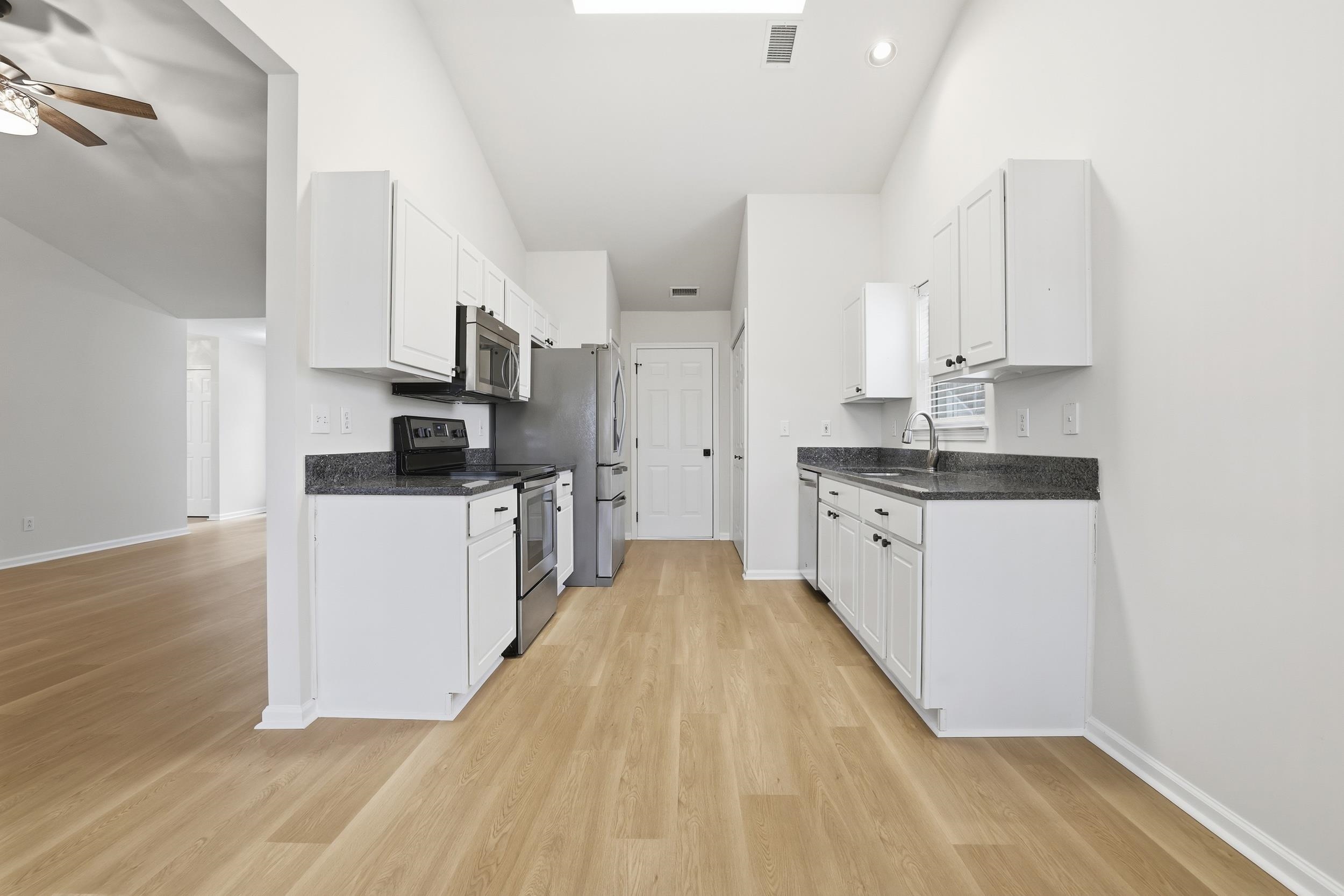 4566 Fringetree Drive Murrells Inlet, SC 29576 - Photo 10 of 36 Kitchen featuring stainless steel appliances, white cabinets, light wood-style flooring, dark stone counters, and a ceiling fan