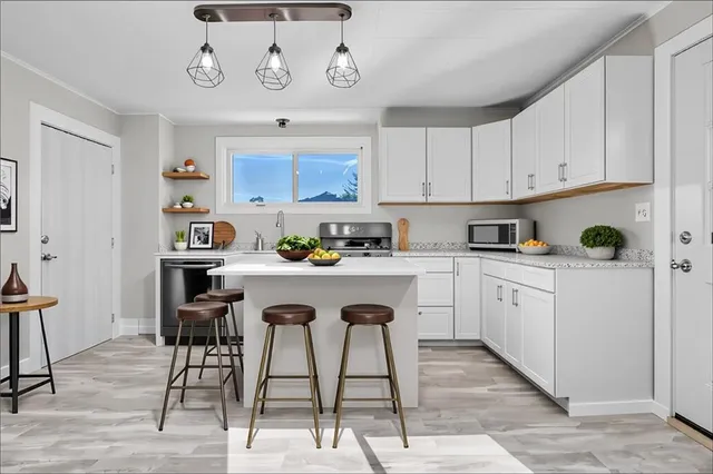 a kitchen with granite countertop a stove a sink and white cabinets with wooden floor