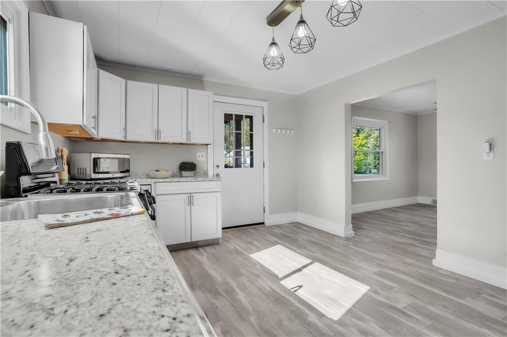1229 McKee Road Crescent, PA 15046 - Photo 7 of 32 a kitchen with granite countertop a stove a sink and white cabinets with wooden floor