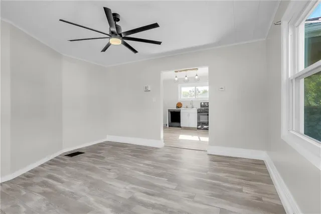 an empty room with wooden floor ceiling fan and windows