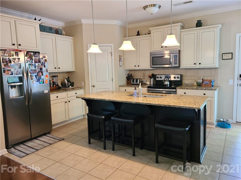 7160 Meyer Road Fort Mill, SC 29715 - Photo 3 of 10 a kitchen with stainless steel appliances a sink a stove a refrigerator cabinets and chairs
