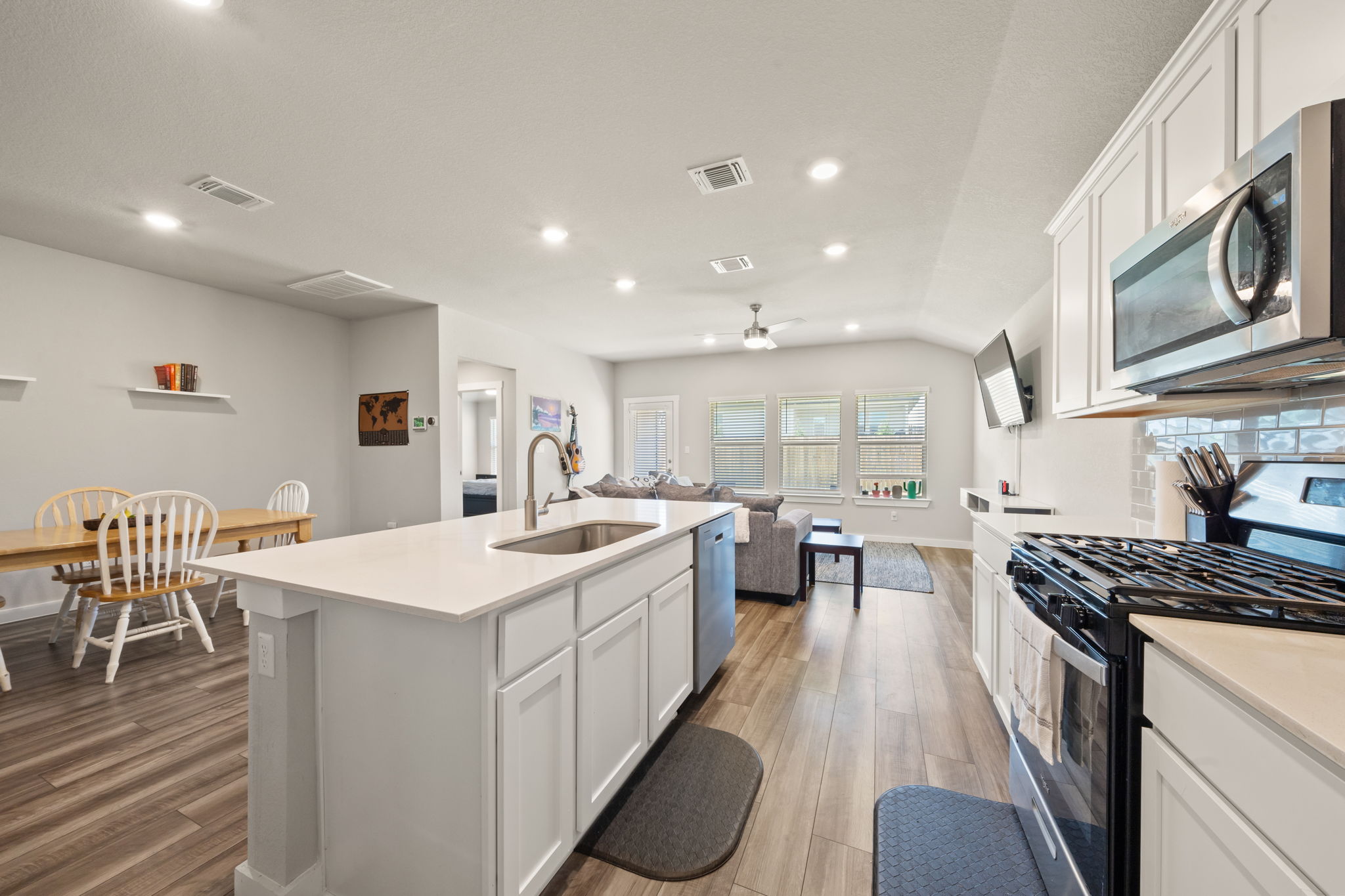 1117 Tipton Street Georgetown, TX 78633 - Photo 6 of 40 Modern kitchen featuring white cabinetry, stainless steel appliances, a white island with an undermount sink, and wood-finish flooring