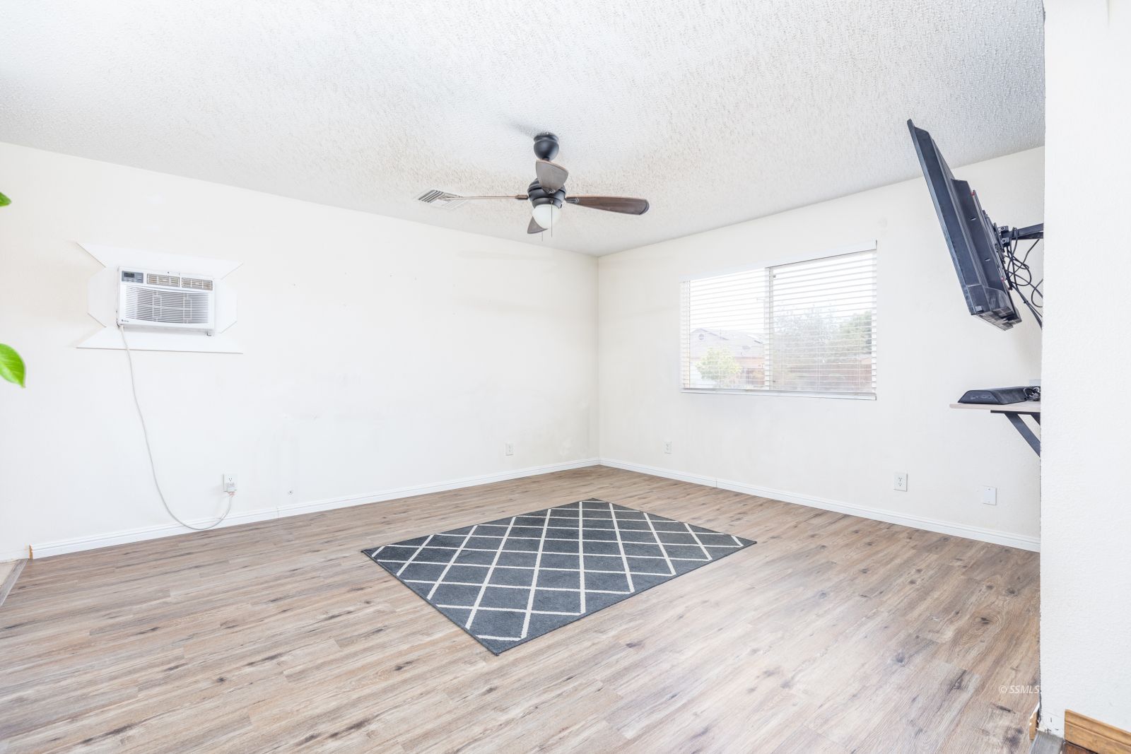 918 West Hughes Avenue Ridgecrest, CA 93555 - Photo 7 of 25 an empty room with wooden floor ceiling fan and windows