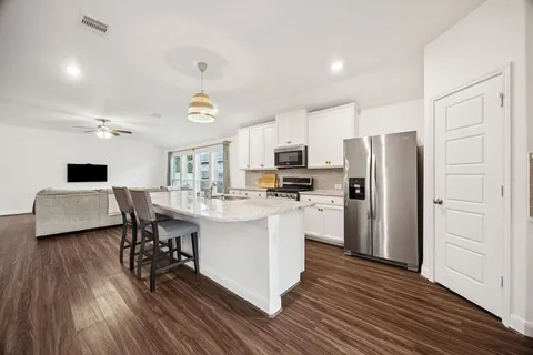 a kitchen with stainless steel appliances a refrigerator a stove a sink dishwasher and a dining table with wooden floor