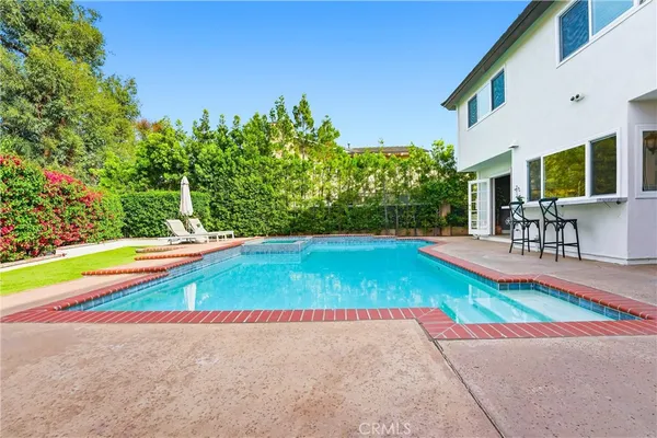 a view of pool with lawn chairs and large trees